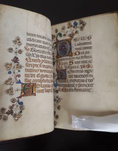 Photograph of a page from a 15th century book of hours. Calligraphy, decorative designs, and the use of gold have been employed to adorn the page.