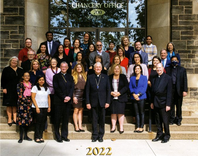 Group photograph with rows of people standing on the front stairs of a building.